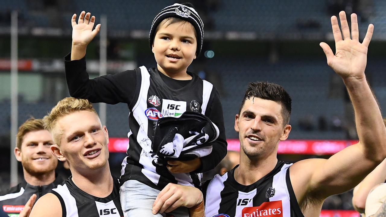 Kyron McGuire is chaired off the ground by Adam Treloar and Scott Pendlebury. Photo: Quinn Rooney/Getty Images.