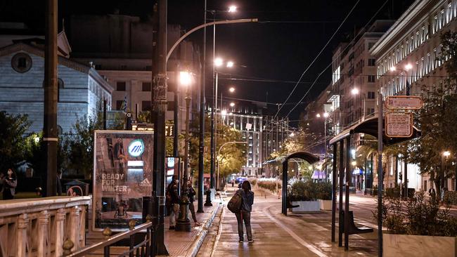 A woman waits for a bus in a deserted street of central Athens on November 7, 2020. Picture: LOUISA GOULIAMAKI / AFP)