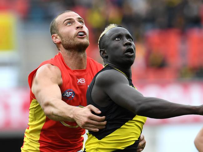 Jarrod Witts of the Suns (left) and Mabior Chol of the Tigers watch the ball during the Round 16 AFL match between the Gold Coast Suns and the Richmond Tigers at Metricon Stadium on the Gold Coast, Saturday, July 6, 2019. (AAP Image/Dan Peled)