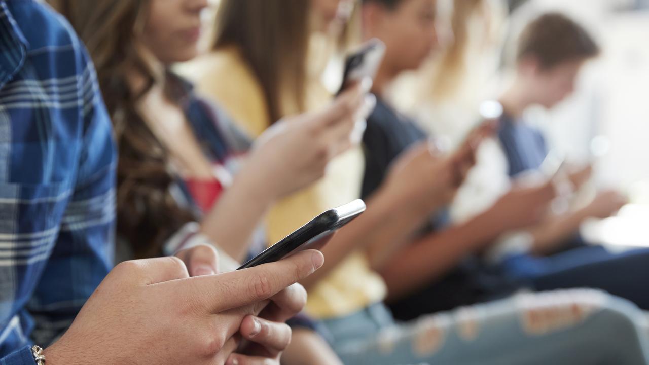 Close Up Of A Line Of High School Students Using Mobile Phones