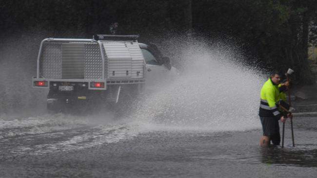 Council workers clear a drain as a car drives through floodwaters in Lewisham. Picture: (AAP Image/Dean Lewins