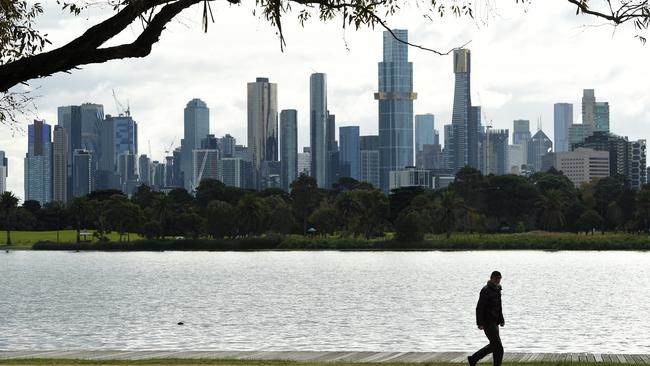 MELBOURNE, AUSTRALIA - NewsWire Photos June 02, 2022: A man walks around Albert Park Lake with the Melbourne skyline in the background on a day when the city temperature is not expected to go above 12'. Picture: NCA NewsWire / Andrew Henshaw