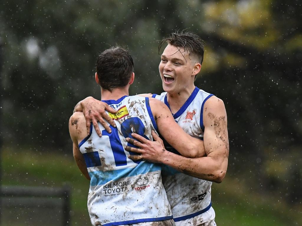 Two muddied Kilmore players celebrate a goal. Pictures: Nathan McNeill.