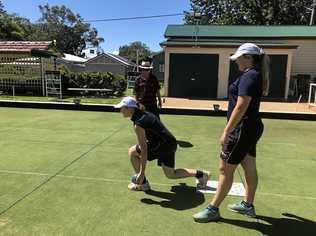 ROLL UP: Fairholme College students Sophie Mossman and Charlie Keegan practice their lawn bowls skills under the watchful eye of a Toowoomba Bowls Club member. Picture: Contributed