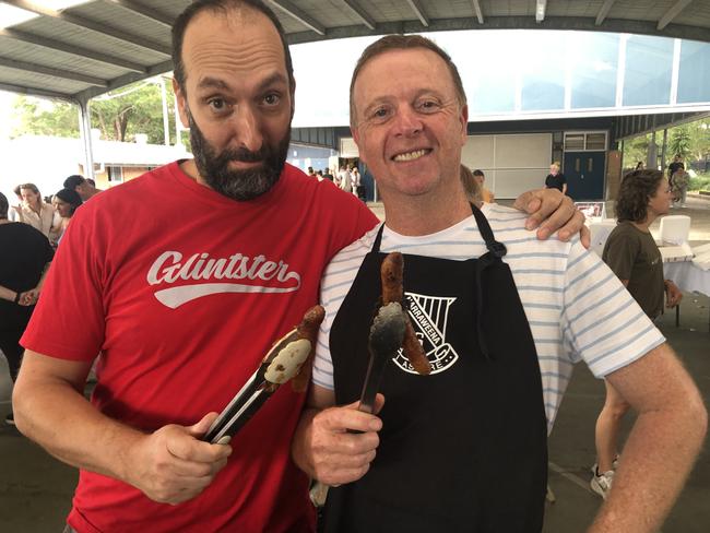 'My sausage is better than yours': Volunteers Ed Hurst and Mark Windser on the BBQ at the polling booth in Narraweena Public School on Saturday, to raise money for the school's musical string ensemble group. Picture: Jim O'Rourke