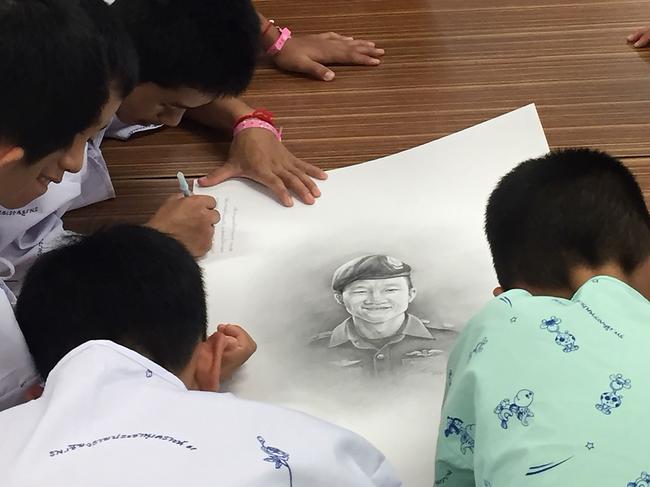 Members of the rescued team at hospital in Chiang Rai province writing messages on a drawing of former Navy SEAL diver Saman Kunan who died. Picture: AFP