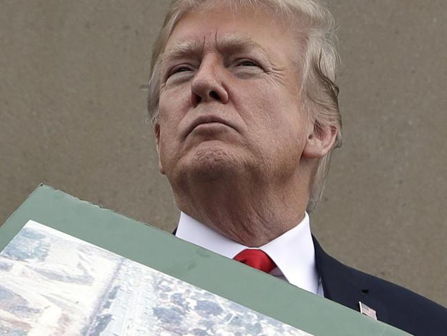 President Donald Trump holds a photo of the border area as he reviews border wall prototypes, Tuesday, March 13, 2018, in San Diego. Rodney Scott, the Border Patrol's San Diego sector chief, helps to hold the print. (AP Photo/Evan Vucci)