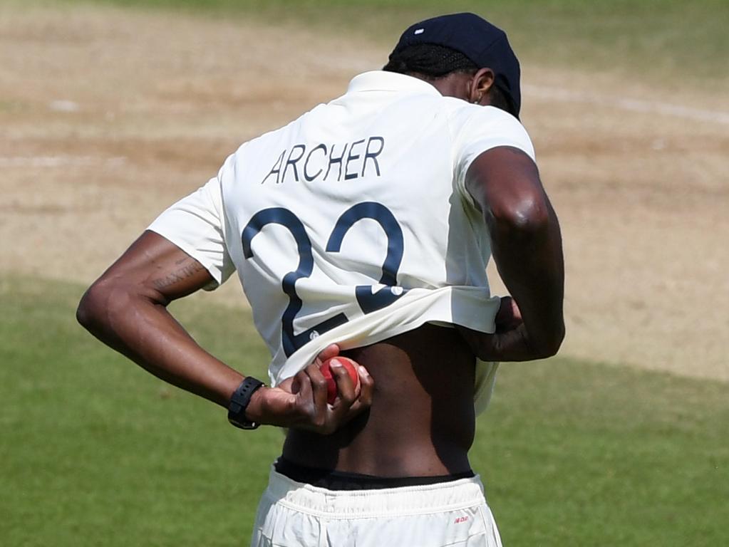 Jofra Archer lifts his shirt to wipe sweat on the ball.