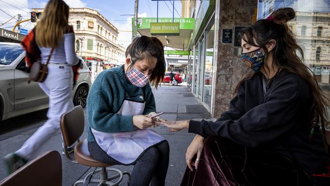 A woman gets her nails done outside a beauty salon. Picture: David Geraghty