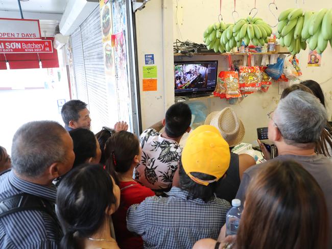 A crowd gathers to examine CCTV footage in a store near the attack. Picture: David Swift.