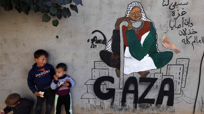 Displaced Palestinian children stand next to a mural painting by artist Amal Abo in Rafah in the southern Gaza Strip. Picture: AFP