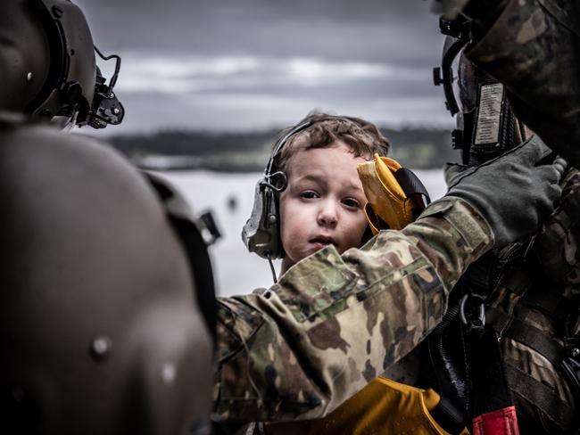 An Australian Army aircrewman from the School of Army Aviation and a young child are winched aboard an MRH-90 Taipan helicopter near Lismore.