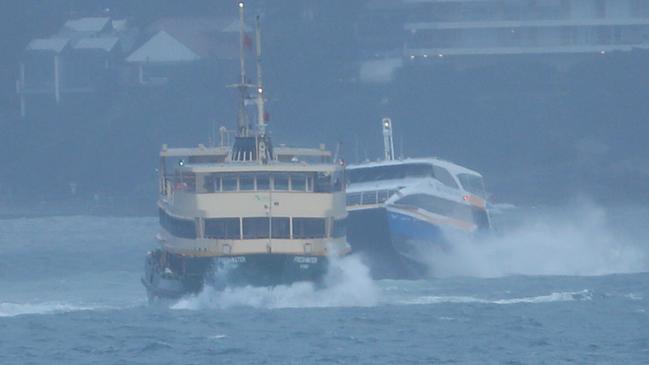 The Manly ferry and the Many Fast Ferry battle the swell across Sydney Heads this morning. Picture: John Grainger