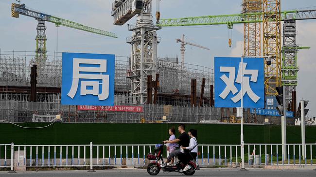 People commute in front of the under-construction Guangzhou Evergrande football stadium in Guangzhou, in China's southern Guangdong province. Picture: AFP