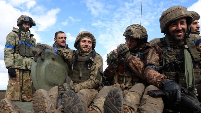 Ukrainian soldiers sit atop a personnel armoured carrier in the Donetsk region smiling after President Volodymyr Zelenskyy said on a key town located in one of four Ukrainian regions annexed by Russia, had been 