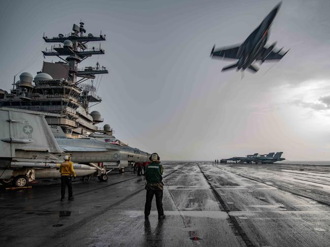 An F/A-18E Super Hornet flies over the flight deck of the USS Ronald Reagan. Picture: US Navy