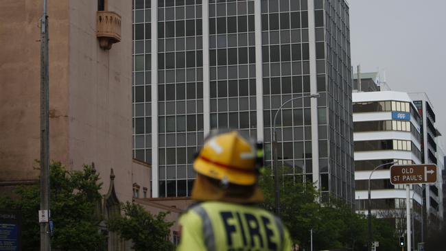 An emergency worker patrols a road cordon in Wellington after officials determined a nine-story office building, centre, is in danger of collapse. Picture: AP//Nick Perry