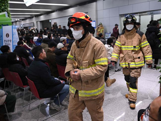 Firefighters walk past people and relatives of passengers of the crashed plane at Muan International Airport. Picture: AFP