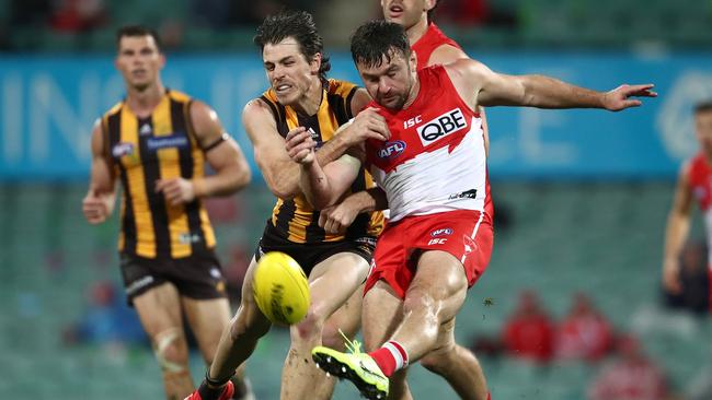 SYDNEY, AUSTRALIA - JULY 25: Sam Gray of the Swans kicks whilst being tackled by Isaac Smith of the Hawks during the round 8 AFL match between the Sydney Swans and the Hawthorn Hawks at the Sydney Cricket Ground on July 25, 2020 in Sydney, Australia. (Photo by Cameron Spencer/Getty Images)