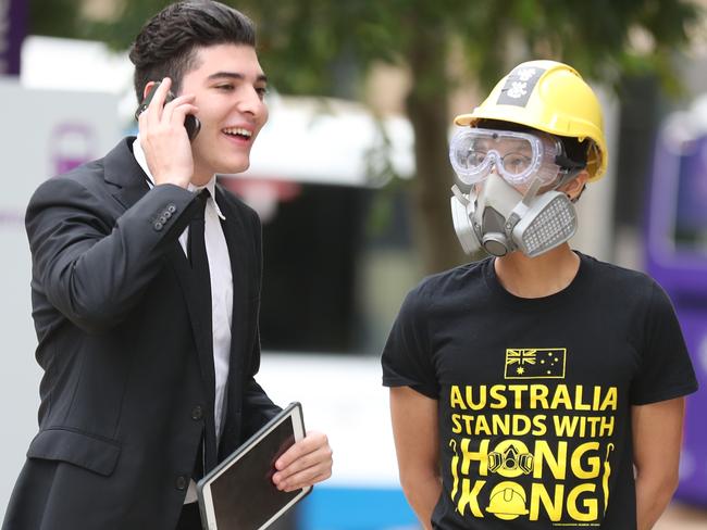 Drew Pavlou (left) speaks on the phone outside the University of Queensland as a support looks on. Picture: Annette Dew