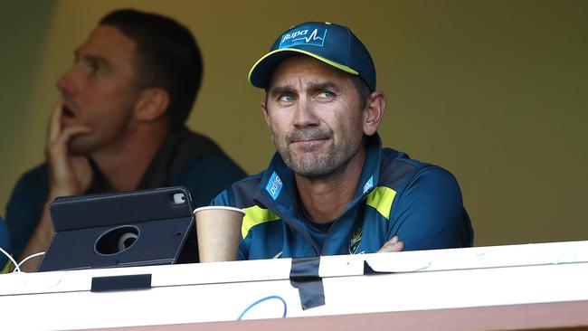 Justin Langer watches on Shaun Marsh sits in the background.