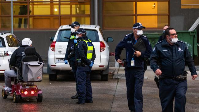 Police speak to a resident at housing commission flats in the suburb of Flemington, where a coronavirus outbreak has been recorded. Picture: Getty Images