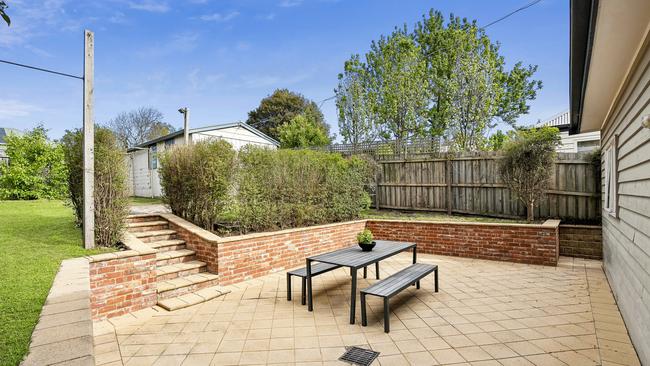 A large patio sits behind the house, looking up to the deep back yard.