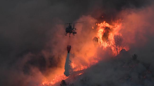 A helicopter struggles against a fire that spread near Vitrolles, southern France. Picture: AFP