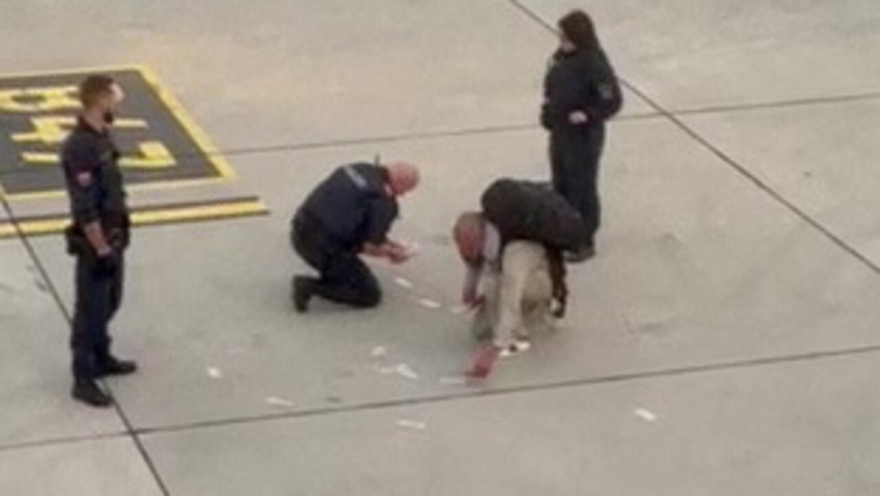 Video caught the bizarre moment a woman threw cash at a man on a runway after being escorted off a plane. Picture: SWNS / MEGA