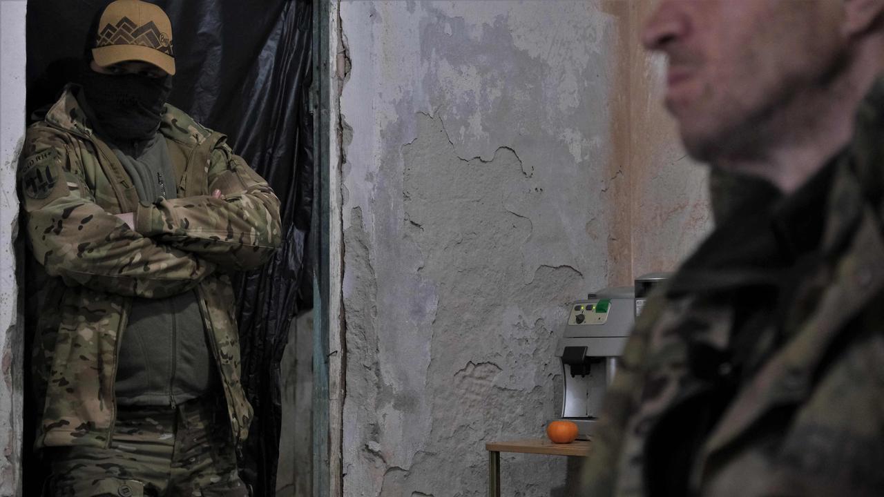 A Ukrainian serviceman (left) looks on while a member of a Russian paramilitary group sits in an interrogation room, having been captured. Picture: Sergey Shestak/AFP