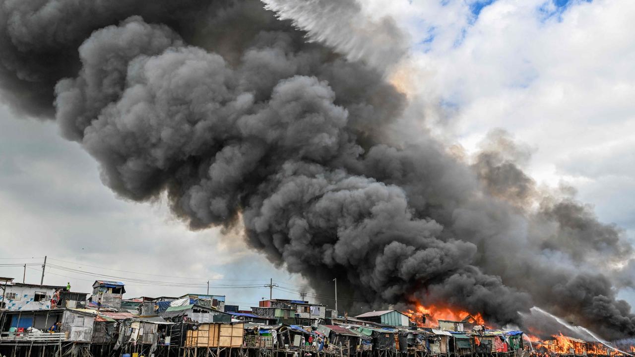 A Philippine Air Force helicopter drops water over burning houses. (Photo by JAM STA ROSA / AFP)