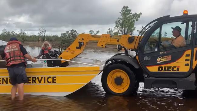 Outside Normanton on the Croyden side of Norman River, Troy Gallagher (left) and John Bentvelzen (centre) steady a State Emergency Service flood boat while Bradley Hawkins loads goods using an all-terrain forklift. Picture: Ashley Gallagher