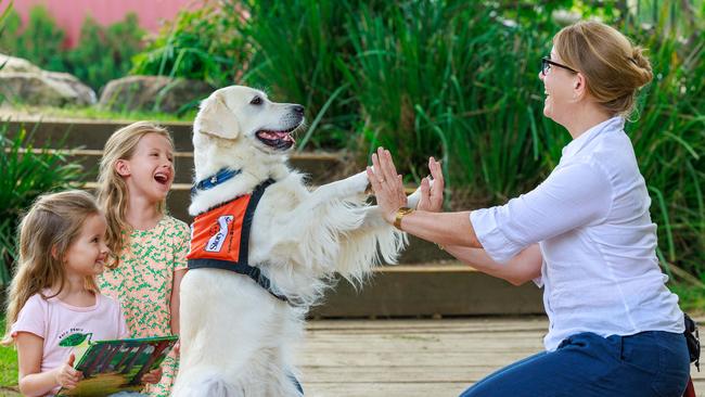 Carla, 5, and Lea Schell, 5, with Nicole Rosenthal and her golden retriever Lotti, a volunteer with the Story Dogs Reading Program, at the German International School, Terry Hills, Sydney. Picture: Justin Lloyd