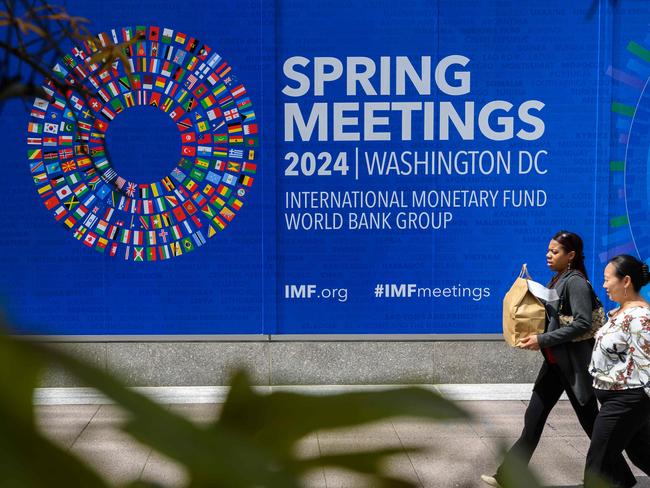 Pedestrians walk past the International Monetary Fund (IMF) headquarters on April 12, 2024, in Washington, DC, ahead of the IMF/World Bank 2024 Spring Meetings. (Photo by MANDEL NGAN / AFP)