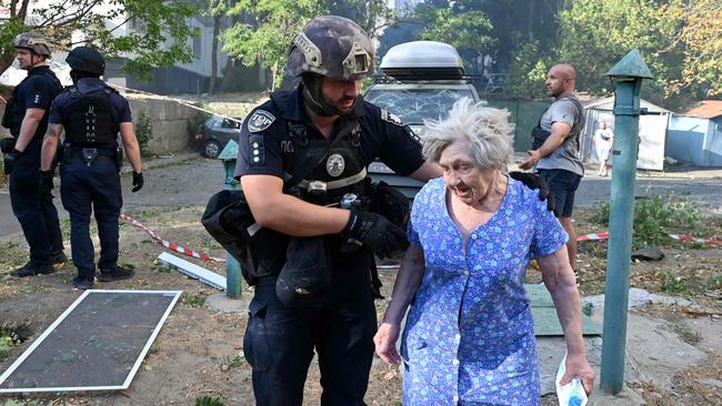 A Ukrainian police officer leads an elderly woman away from the site of a missile attack in Kharkiv on Sunday (Monday AEST). Picture: AFP