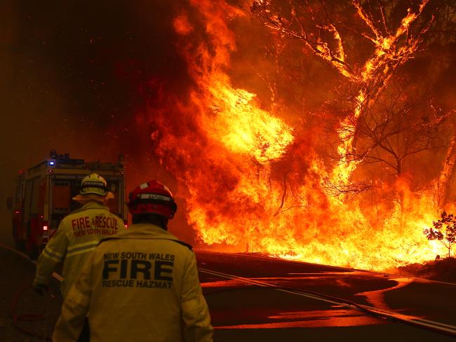 SYDNEY, AUSTRALIA - DECEMBER 19: Fire and Rescue personal run to move their truck as a bushfire burns next to a major road and homes on the outskirts of the town of Bilpin on December 19, 2019 in Sydney, Australia. NSW Premier Gladys Berejiklian has declared a state of emergency for the next seven days with ongoing dangerous fire conditions and almost 100 bushfires burning across the state. It's the second state of emergency declared in NSW since the start of the bushfire season.  (Photo by David Gray/Getty Images) *** BESTPIX ***