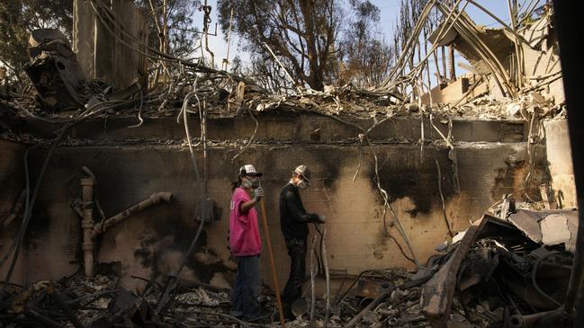 Kaegan Baron, left, and Oliver Braren sift through the home of Kaegan’s mother after it was destroyed by the Palisades Fire in the Pacific Palisades neighbourhood. Picture: AP Photo