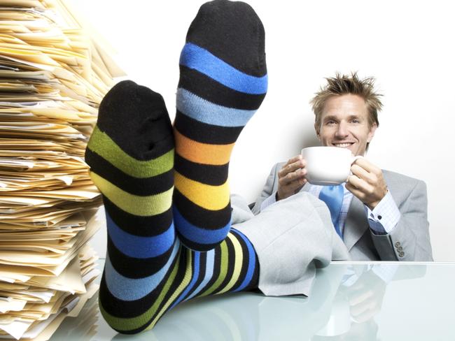 Undated : generic office worker wearing striped socks with his feet on a desk, holding a large cup of coffee / tea, stack of paperwork on desk. ISTOCK IMAGE. ONE TIME USE ONLY