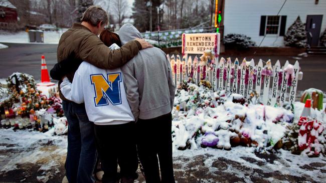 Members of the Rutter family embrace early Christmas morning as they stand near memorials at the Sandy Hook firehouse in Newtown, Connecticut in 2012. Picture: AP