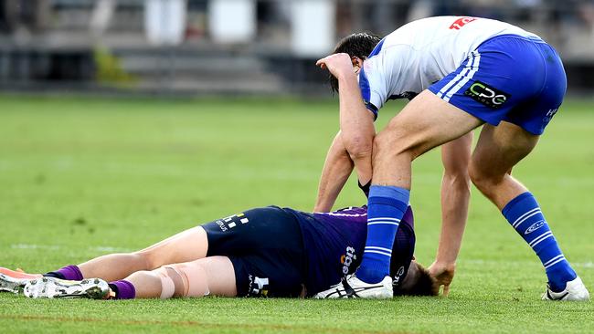 Lachlan Lewis of the Bulldogs checks on Cameron Munster of the Storm.