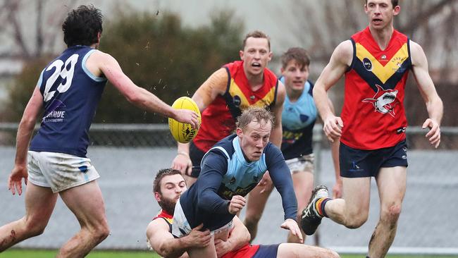 Football. Southern Football League. Dodges Ferry V Lindisfarne. Daniel Blazely Lindisfarne handballs to teammate Troy Cunliffe while being held by Oscar Dodge Dodges Ferry. Picture: NIKKI DAVIS-JONES