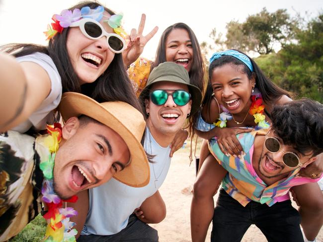 Cheerful and funny selfie of a multiracial group of friends hanging out at a beach festival. Recently graduated colleagues.