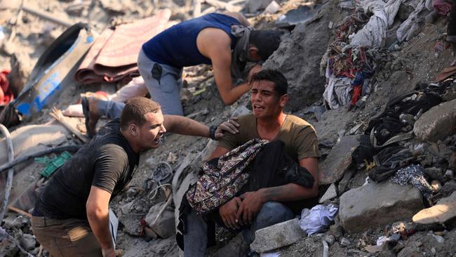 A distraught man holds his mother’s remains wrapped in a blanket after an airstrike on the Bureij refugee camp. Picture: AFP