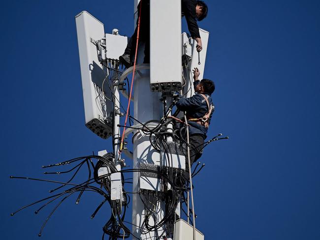 Workers are seen on a 5G tower at Shougang Park, one of the sites for the Beijing 2022 Winter Olympics, in Beijing on December 1, 2021. (Photo by Noel Celis / AFP)