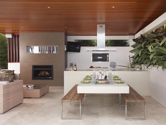 The floating dining table in this outdoor kitchen by Rolling Stone Landscapes is offset by timber bench seats.