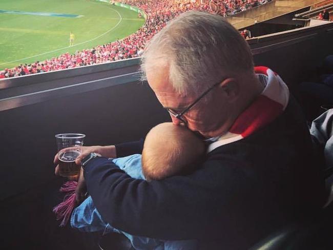 Prime Minister Malcolm Turnbull holds his granddaughter at the Sydney Swans versus Essendon at the SCG.