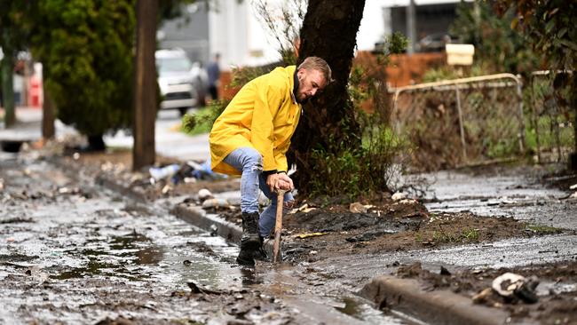 Lismore man Eli Roth clears mud and debris from a drain outside his house on March 29, 2022. Picture: Dan Peled