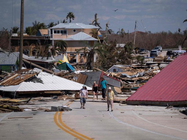 People walk pass destroyed houses and businesses in the aftermath of Hurricane Ian in Matlacha, Florida. Picture: AFP