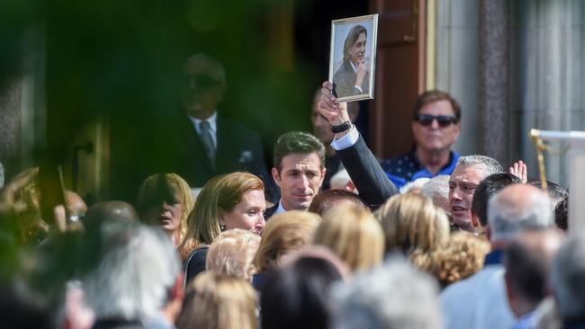 A framed portrait of Mr Acquaro is held up by a mourner to applause. Picture: Jake Nowakowski