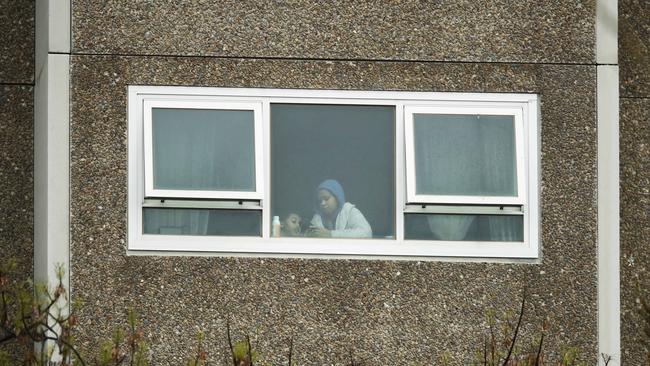 Residents are seen in a window of the locked down public housing tower at 33 Alfred Street, North Melbourne. Picture: NCA NewsWire / Daniel Pockett